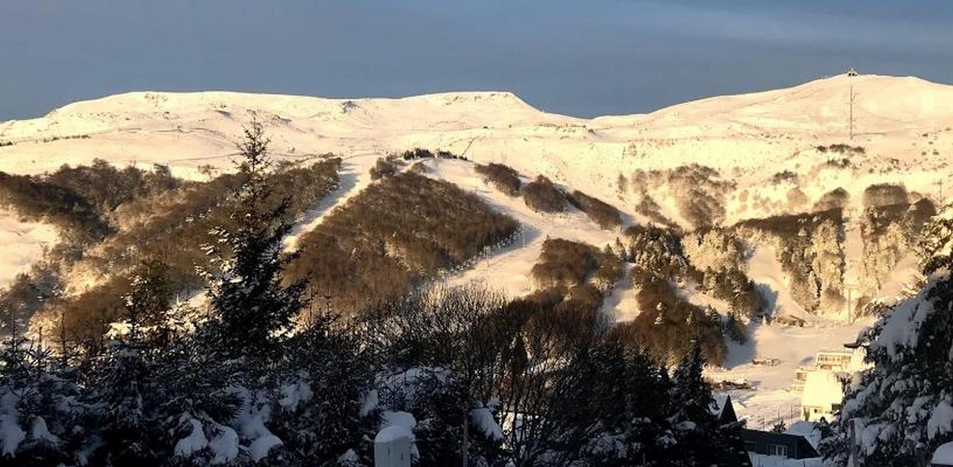 Chalet avec vue sur les pistes de ski de super besse sous la neige en hiver