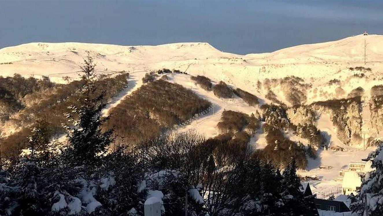 Chalet avec vue sur les pistes de ski de super besse sous la neige en hiver